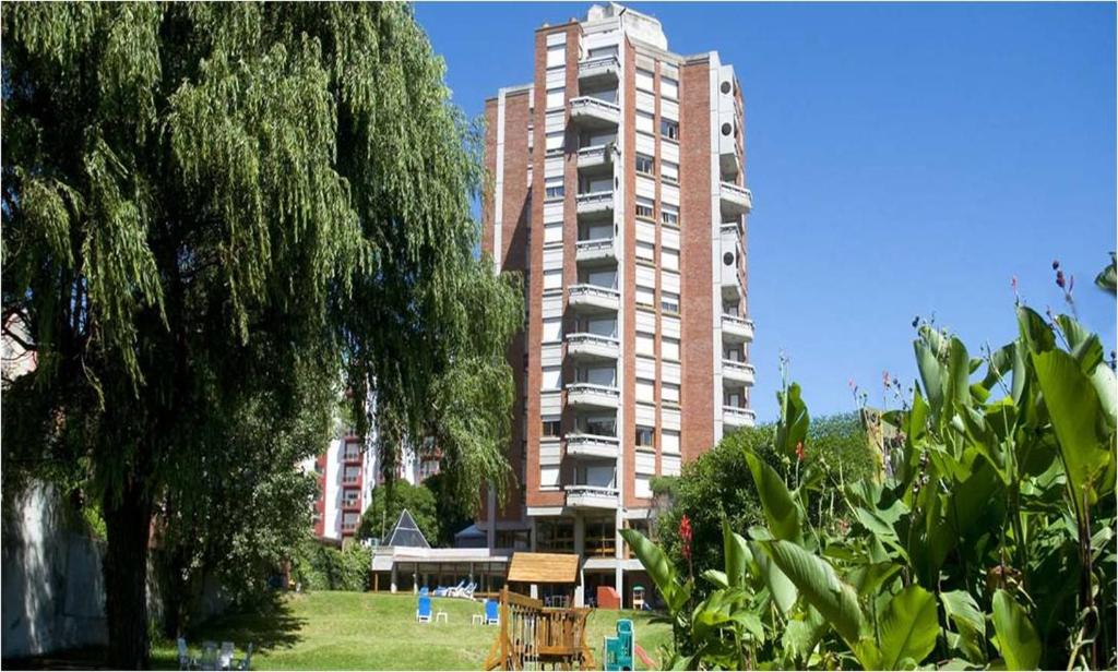 ein großes Apartmenthaus mit einem Park davor in der Unterkunft Terrazas Club Hotel in Villa Gesell