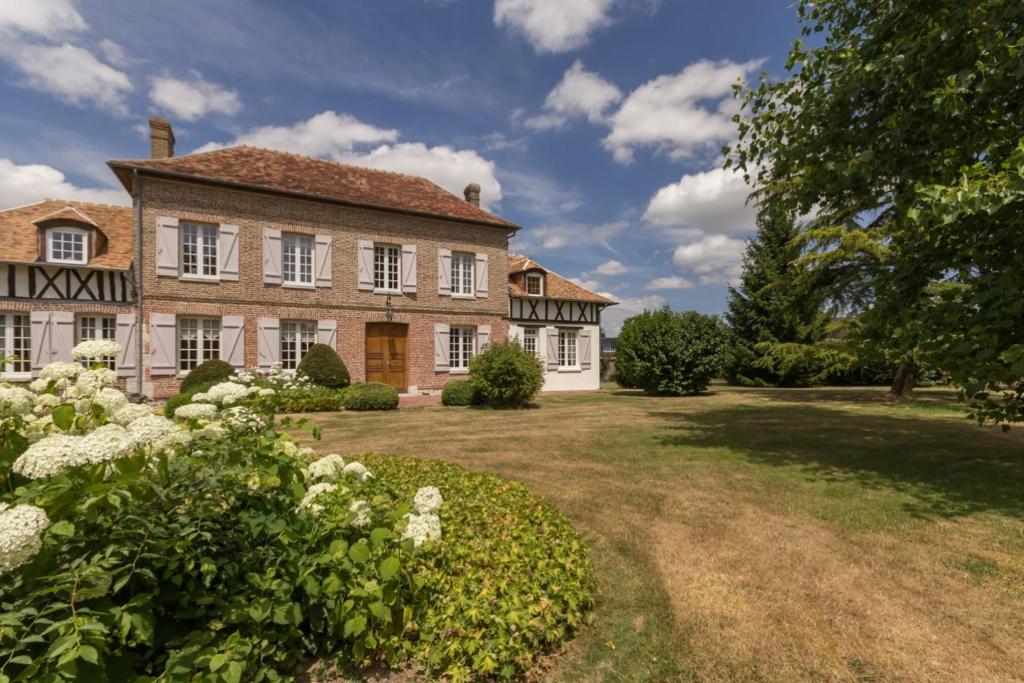 une grande maison en briques avec une cour fleurie dans l'établissement Chambre d'hotes de la Vallee, à Montaure