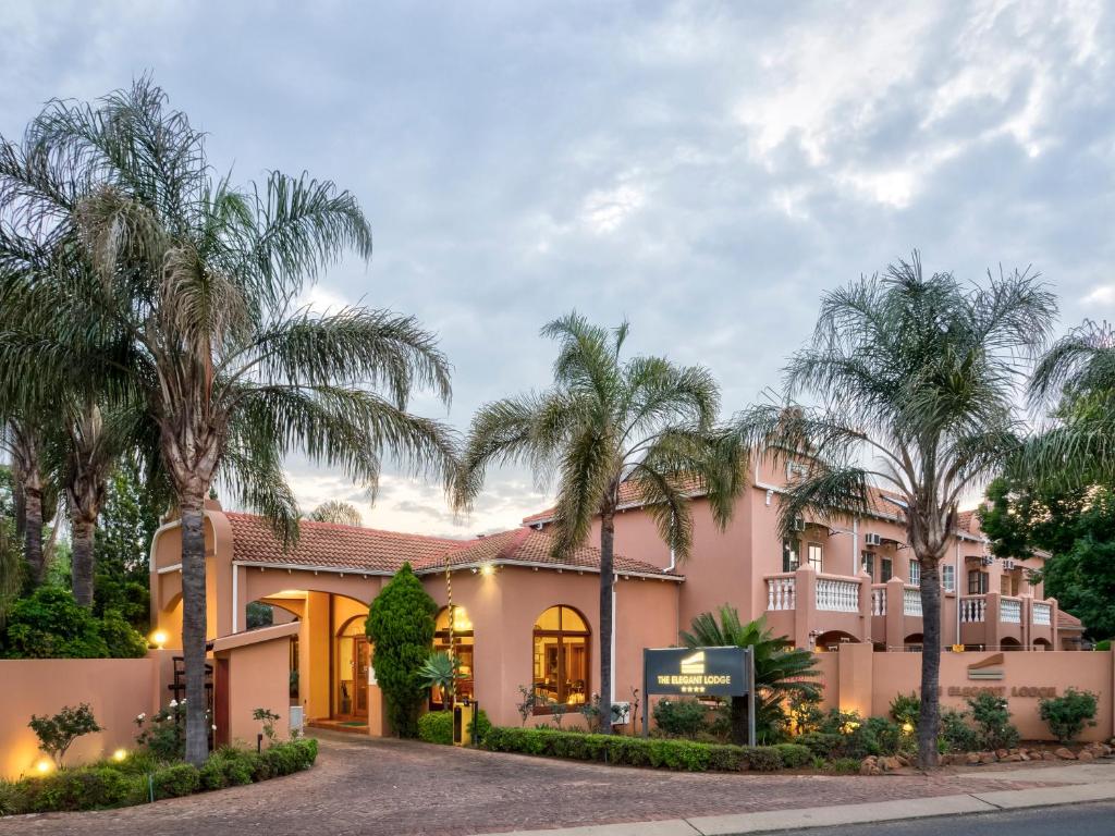 a house with palm trees in front of it at The Elegant Lodge Menlo Park in Pretoria