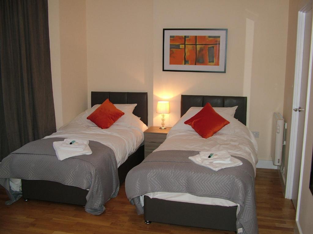 a bedroom with two beds with red pillows at Stratford Apartment in Newmarket