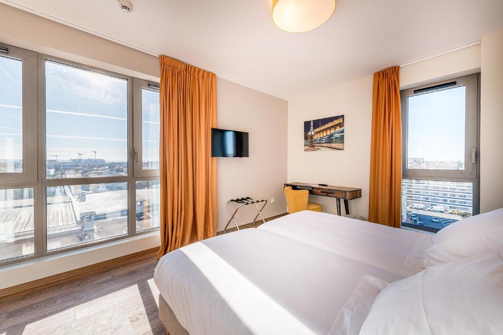 1 dormitorio con 1 cama grande y ventanas grandes en All Suites Bordeaux Centre Marne - Gare Saint-Jean, en Burdeos