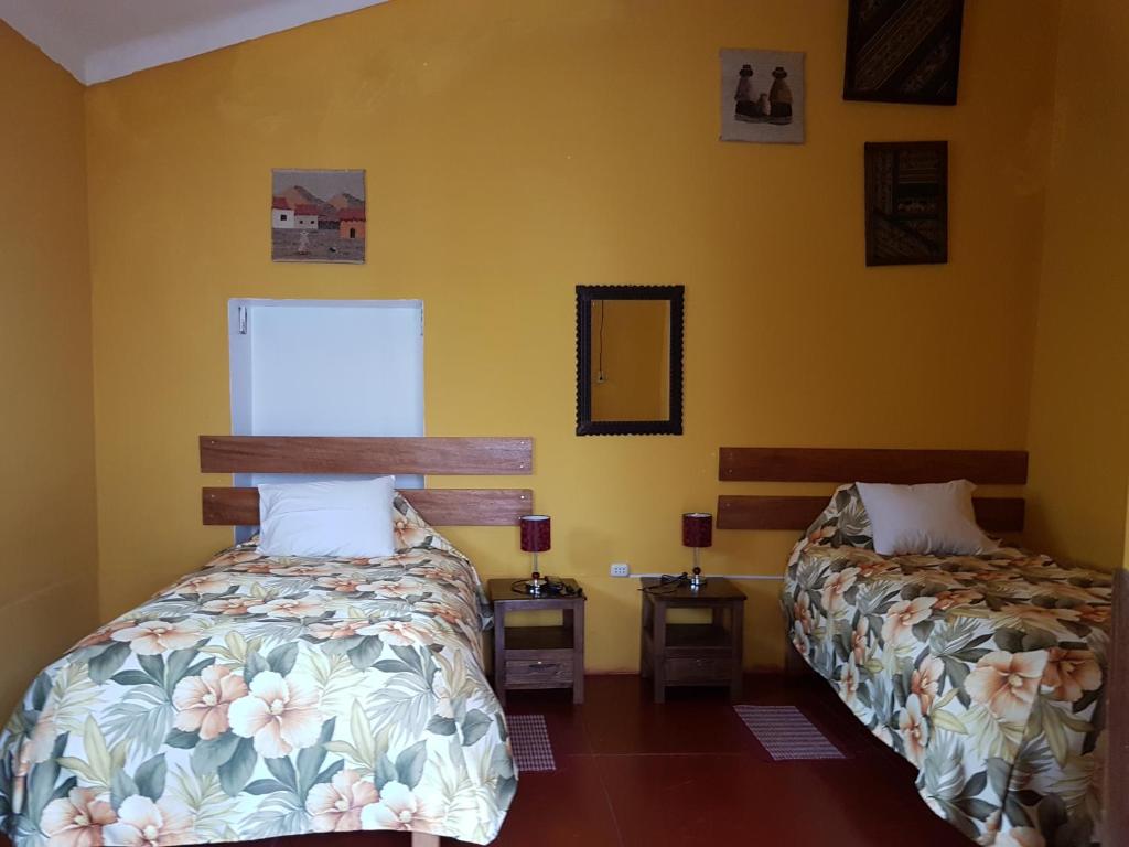 Duas camas num quarto com paredes amarelas em Hospedaje Familiar Kitamayu Pisac em Písac