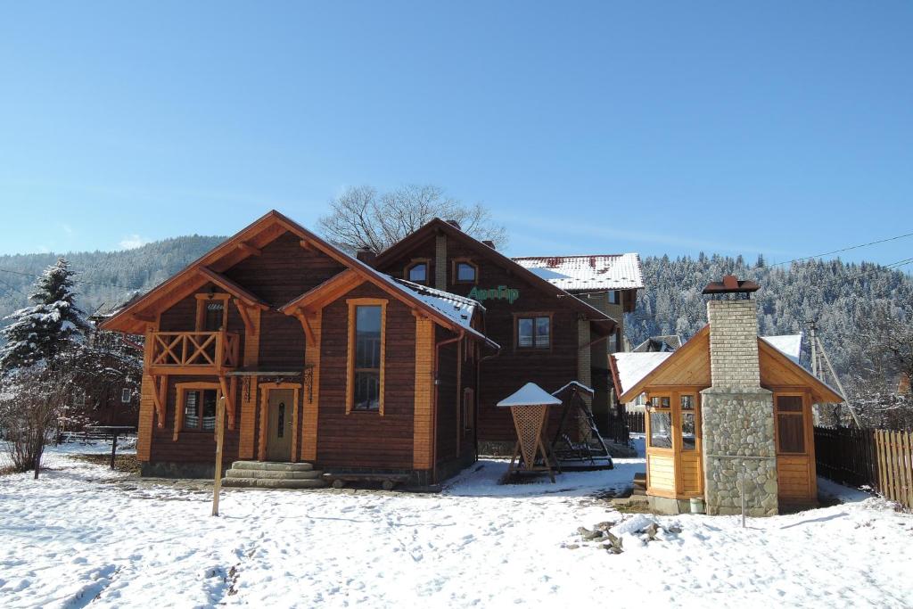 a log cabin in the snow with a chimney at АртГір гостинний двір in Mykulychyn