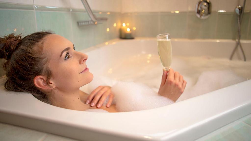 a woman in a bathtub with a glass of champagne at Alpenblick in Zermatt