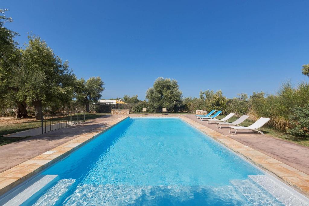 a swimming pool with lounge chairs and trees at Casale Cimino by BarbarHouse in Ostuni