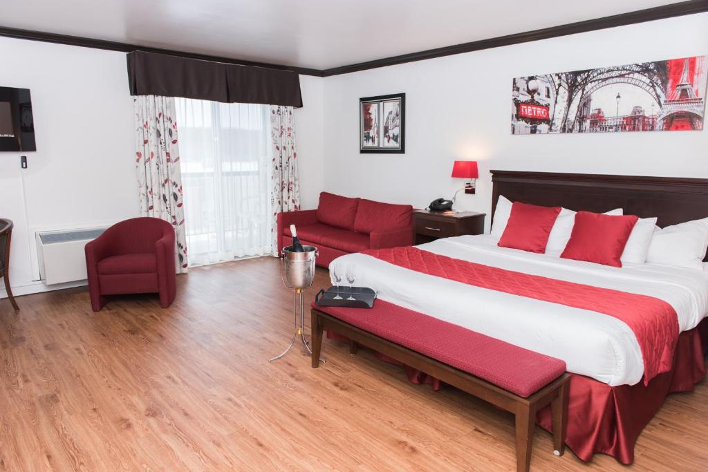 a hotel room with a large bed and red chairs at Hôtel Le Floral in Sherbrooke