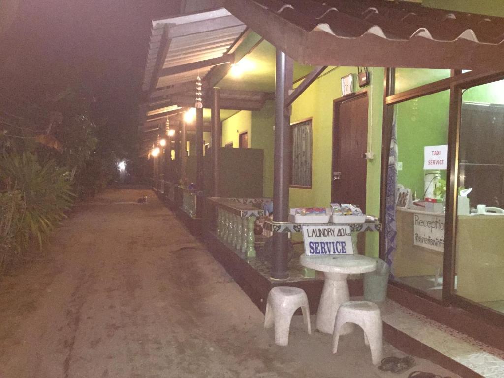 un edificio con una mesa y taburetes en una calle en ABC Bungalow, en Baan Tai