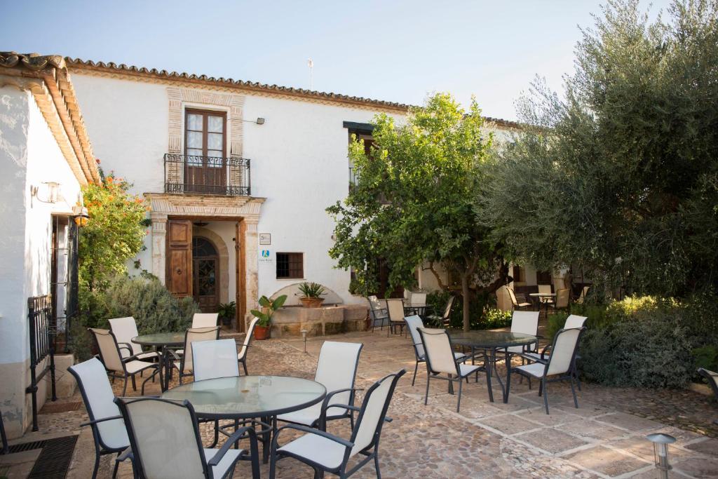 un patio avec des tables et des chaises en face d'un bâtiment dans l'établissement Hotel Rural Hoyo Bautista, à Martín de la Jara