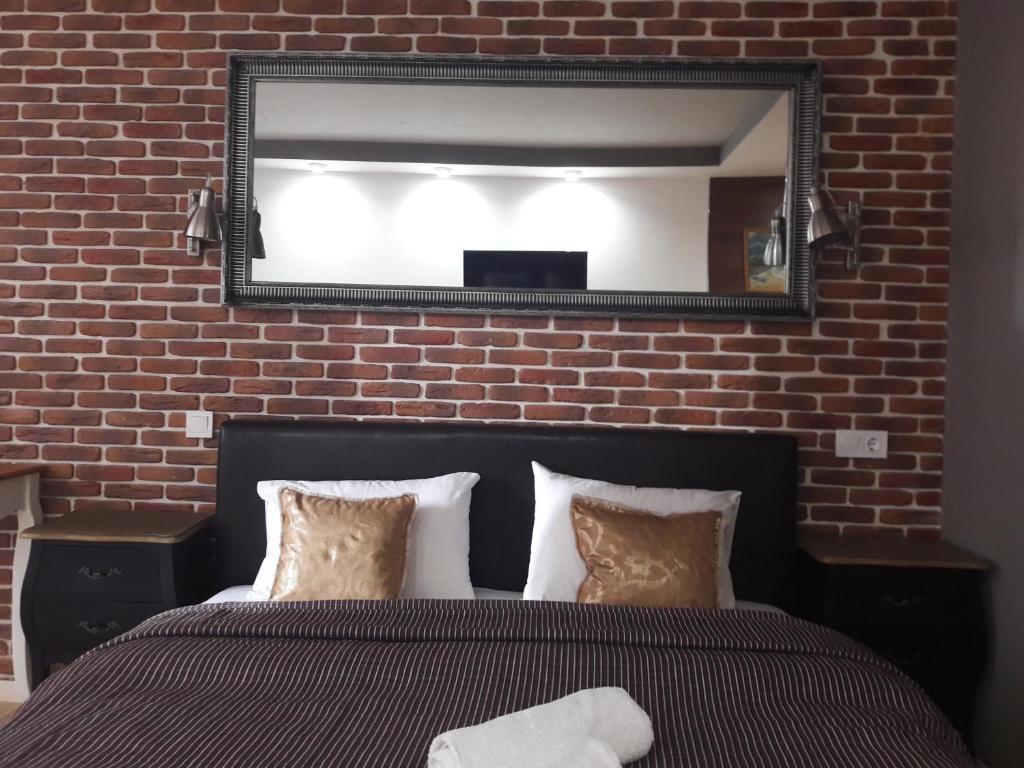 a mirror above a bed in front of a brick wall at Mini Hotel on Demiivska in Kyiv