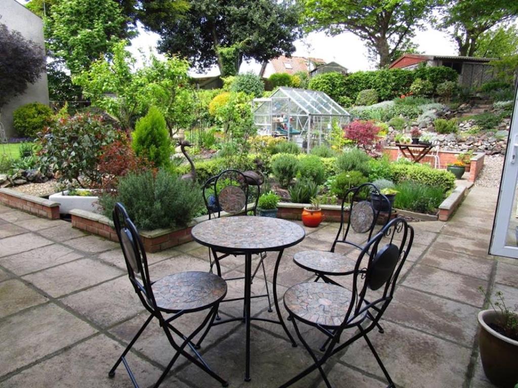 a patio with four chairs and a table in a garden at Southfield House in Hornsea