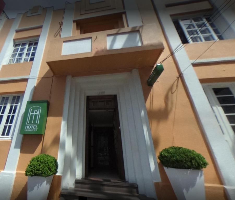 a building with a door and plants in front of it at Hotel Primavera in Bento Gonçalves