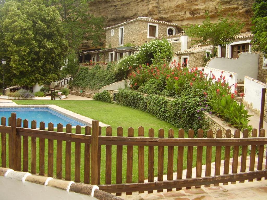 ein Haus mit einem Zaun und einem Garten mit einem Pool in der Unterkunft El Huertecillo in Arriate