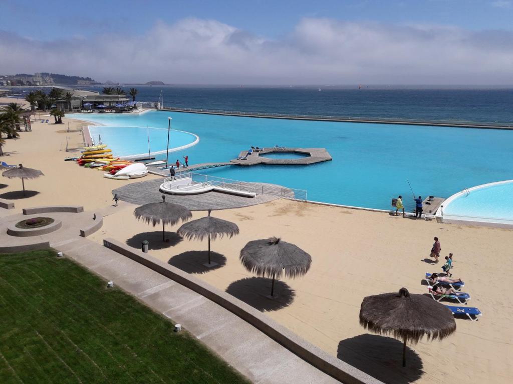 uma vista superior de uma piscina com guarda-sóis e do oceano em San Alfonso del Mar Departamentos em Algarrobo