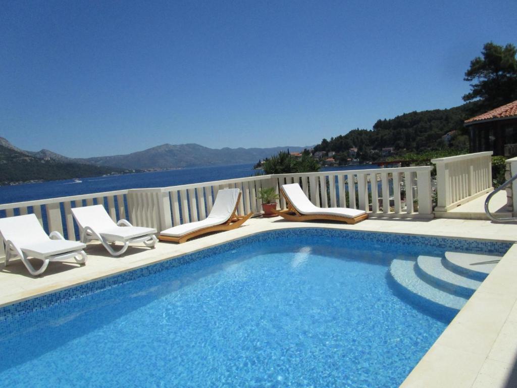 einen Pool mit Stühlen und Blick auf das Wasser in der Unterkunft Vila Tea in Korčula