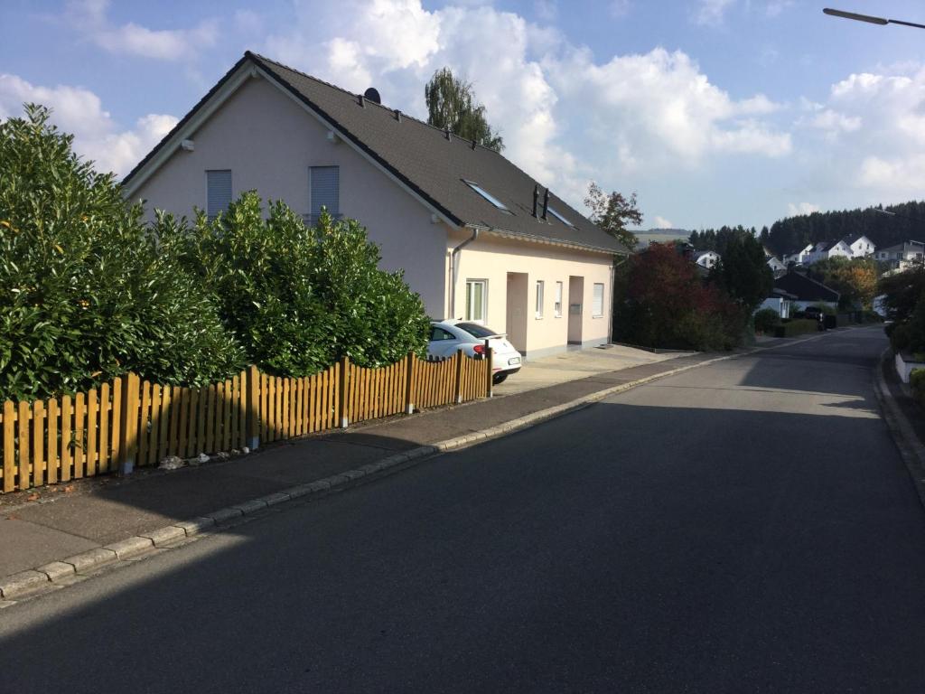 a white house with a fence on the side of a street at FeWo mit Fernblick in Gutweiler