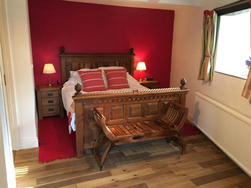 a bedroom with a wooden bed and a red wall at Stoneleigh Barn Bed and Breakfast in Sherborne