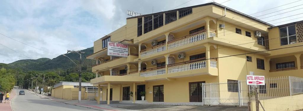 un grand bâtiment jaune avec balcon dans une rue dans l'établissement Hotel Imperador Caldas, à Santo Amaro da Imperatriz