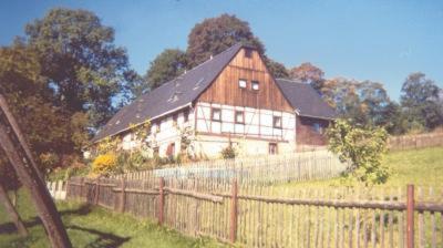 une grande grange en bois dans un champ avec une clôture dans l'établissement Ferienwohnung Richter, à Neundorf