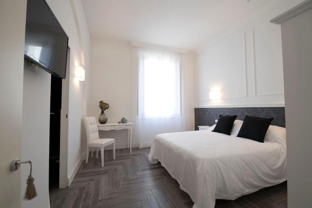 a white bedroom with a white bed and a window at Antica Dimora Pellegrino in Pistoia