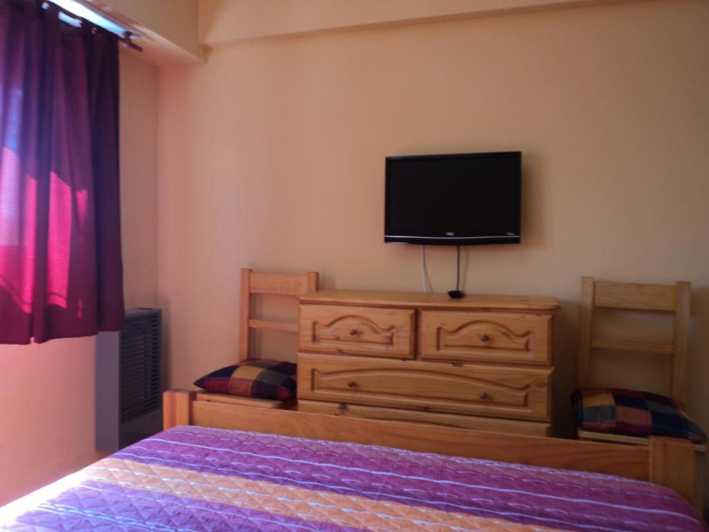 1 dormitorio con cama y vestidor con TV en Edificio Riazor n° IX en San Clemente del Tuyú
