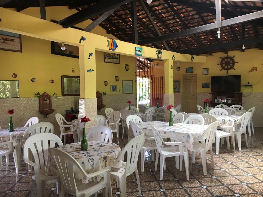 un comedor con mesas blancas y sillas blancas en Algodoal Bela Mar Pousada, en Algodoal