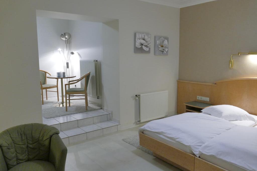 a bedroom with a bed and a chair and a table at Hotel Re'ser Stuff in Roeser