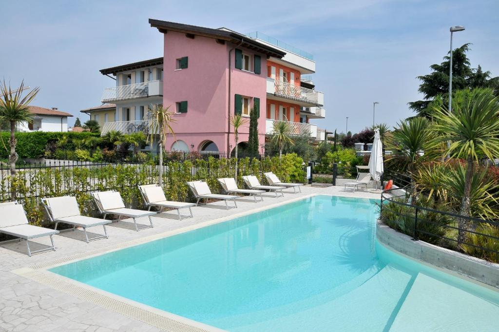 a swimming pool with chairs and a pink building at Acqua Resorts in Sirmione