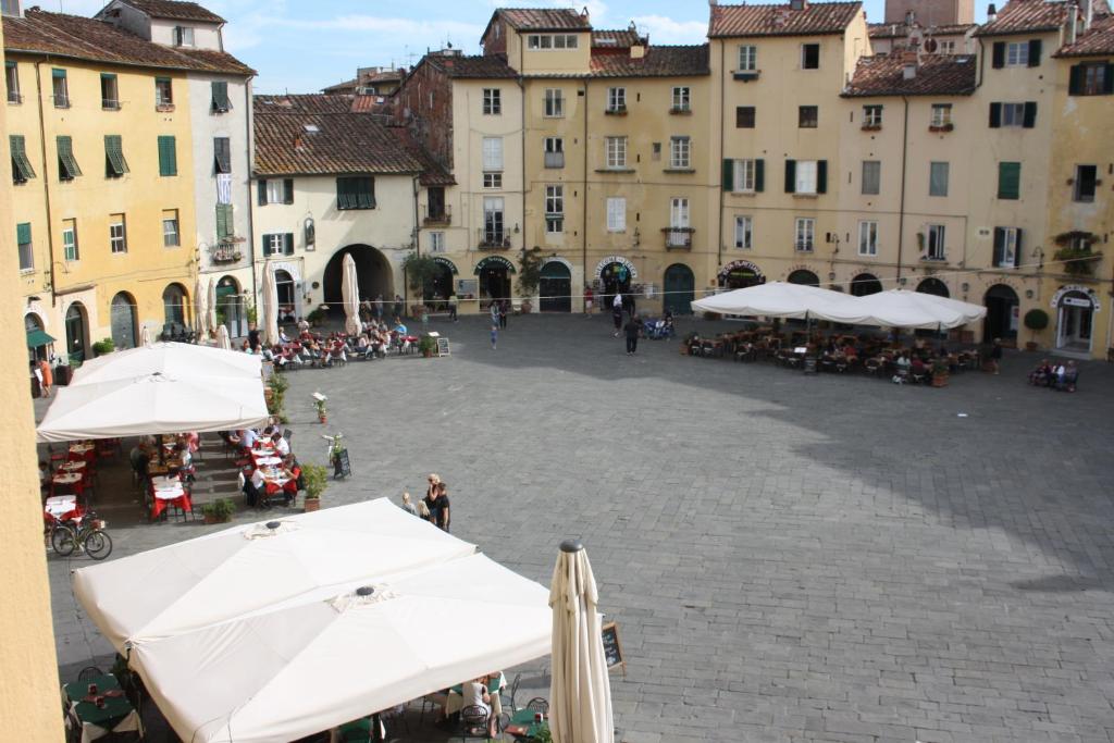 a large courtyard with white umbrellas and buildings at Micheli Suite Anfiteatro Square in Lucca