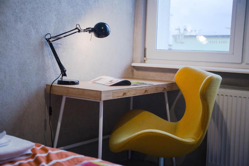 a desk with a lamp and a yellow chair at Apartament w centrum Gdyni in Gdynia