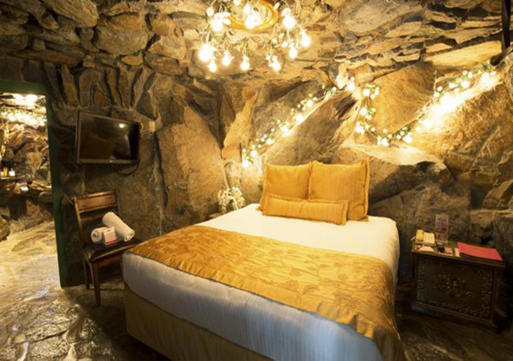 a bedroom with a large bed in a stone room at Madonna Inn in San Luis Obispo