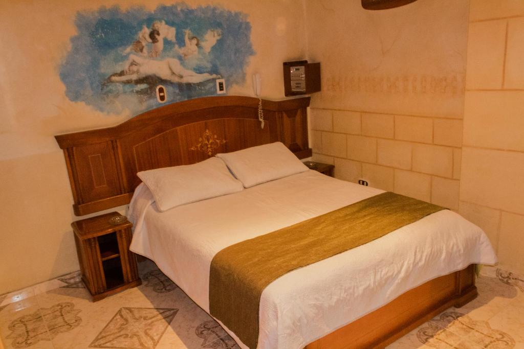 1 dormitorio con 1 cama con una pintura en la pared en Motel Piramides De Cristal, en Bogotá