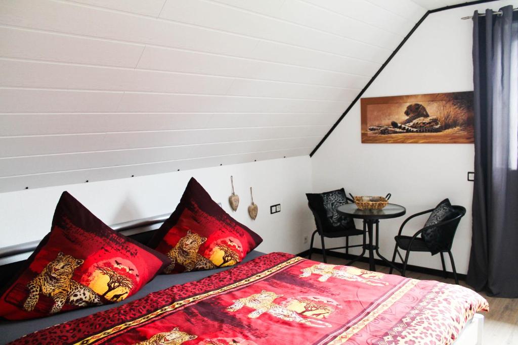 a bedroom with a bed with red pillows and a table at Privatzimmer Lüttingen in Xanten