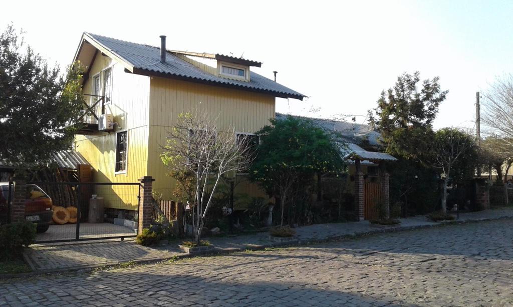 a yellow and white house on a cobblestone street at Casa Rústica - Hospedaria in Canela