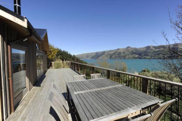 a wooden deck with two chairs and a view of a lake at Mumfords in Akaroa