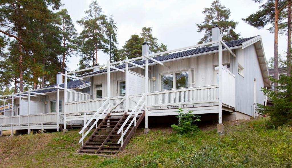 a white house on a hill with trees at Holiday Club Airisto Apartments in Strandby