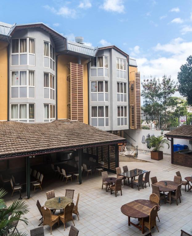 an outdoor patio with tables and chairs and buildings at Hotel Maharajah in Mamoudzou