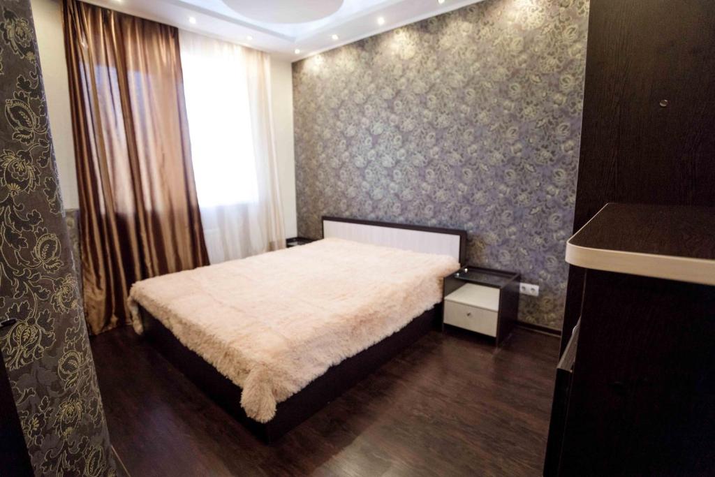 a small bedroom with a bed with a white blanket at Gazovikov 33 Akvapark Evropeyskiy in Tyumen