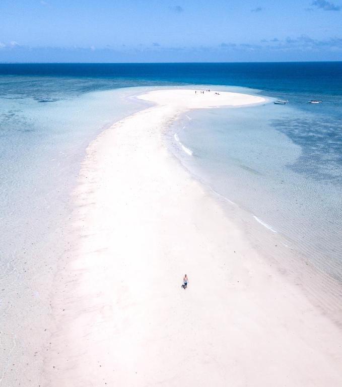 a person standing on a white beach in the ocean at Hotel Maharajah in Mamoudzou