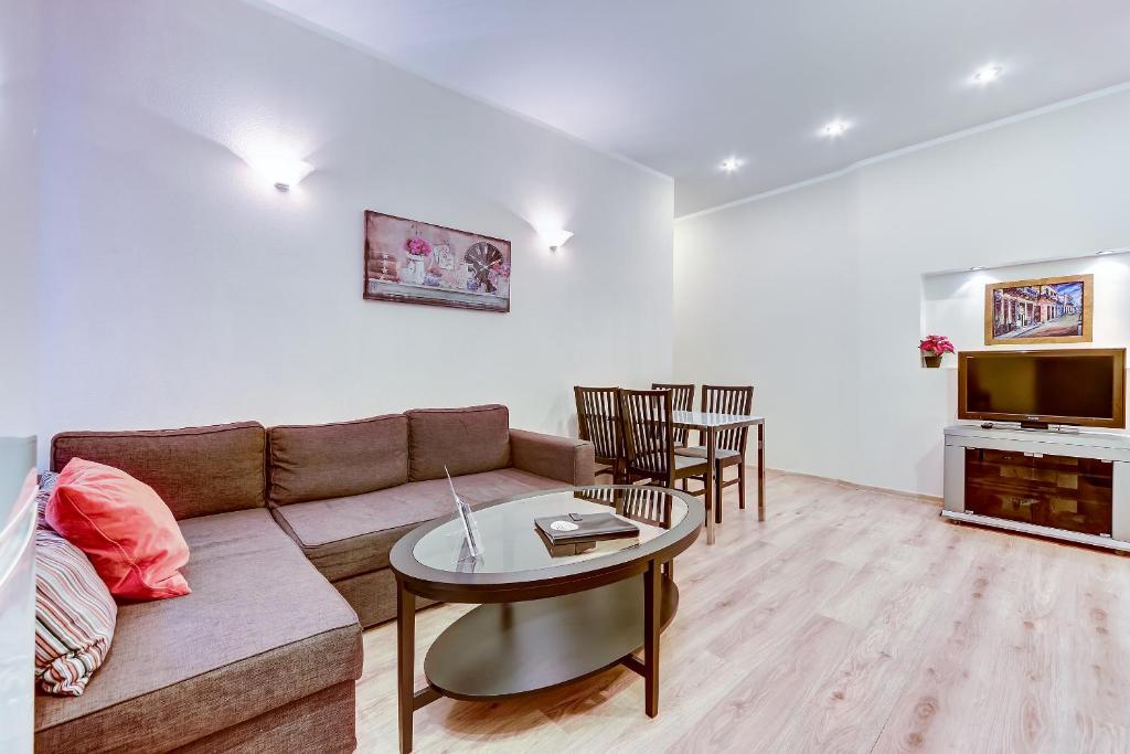 a living room with a couch and a table and a tv at Apartments ERS Moika in Saint Petersburg