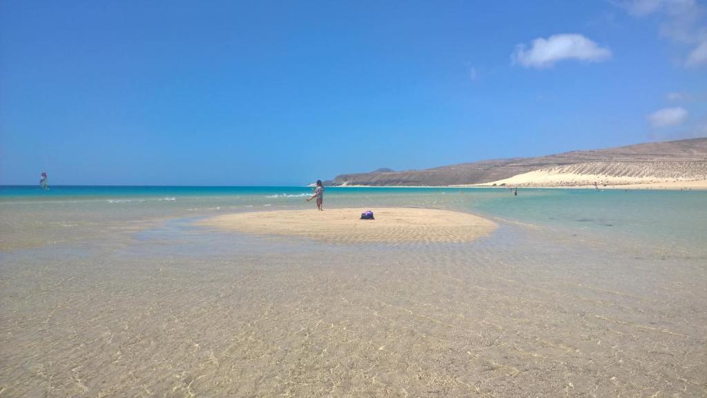 una persona parada en una pequeña isla en el océano en YOUR OCEAN EYES, en Costa Calma
