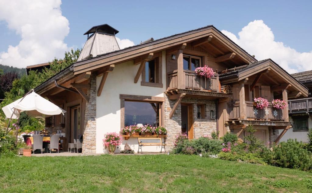 a house with a balcony and flowers on it at Chambres d'Hôtes Chalet Eternel Mont-Blanc in Megève
