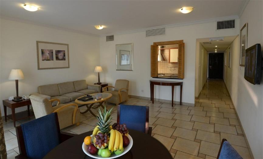 a living room with a table with a bowl of fruit on it at Seashell Julai'a Hotel & Resort Family resort in Al Qulay‘ah