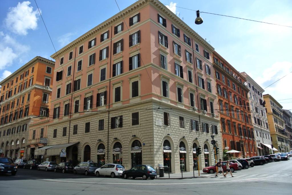 un grand bâtiment dans une rue de la ville avec des voitures garées dans l'établissement Le Petit Real, à Rome