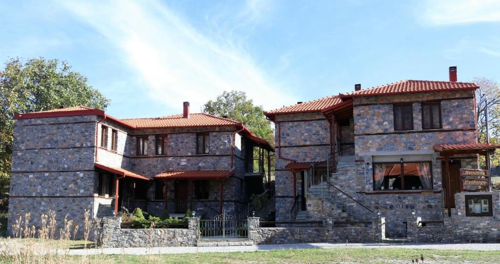 stary kamienny dom z czerwonym dachem w obiekcie Zeidoro w mieście Palaios Agios Athanasios
