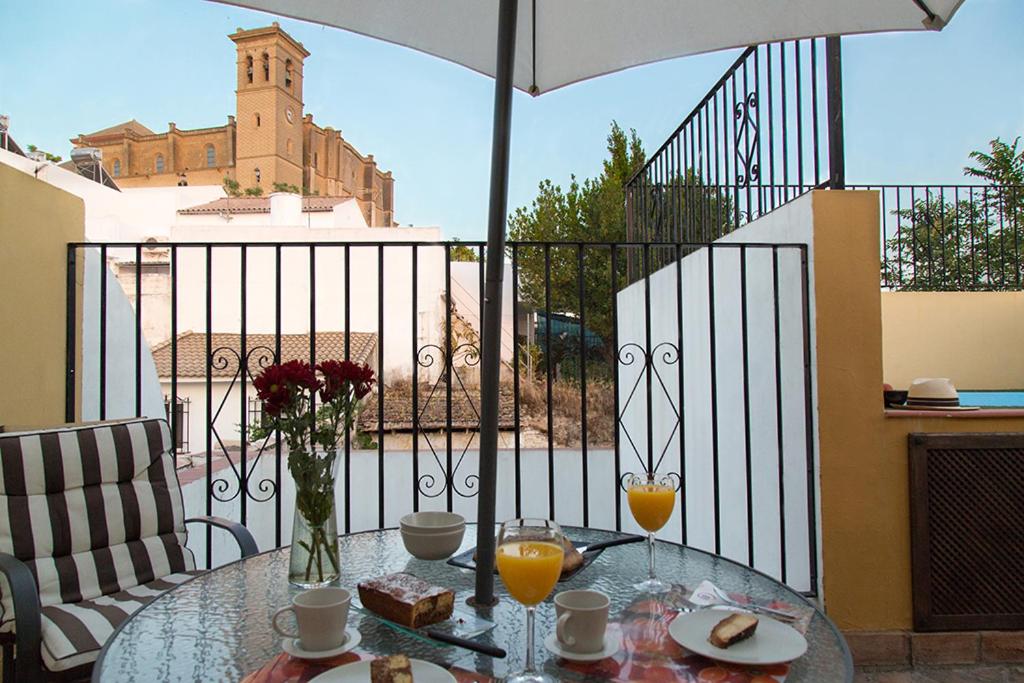 una mesa de cristal con comida y bebida en el balcón en Casa Rural Migolla, en Osuna