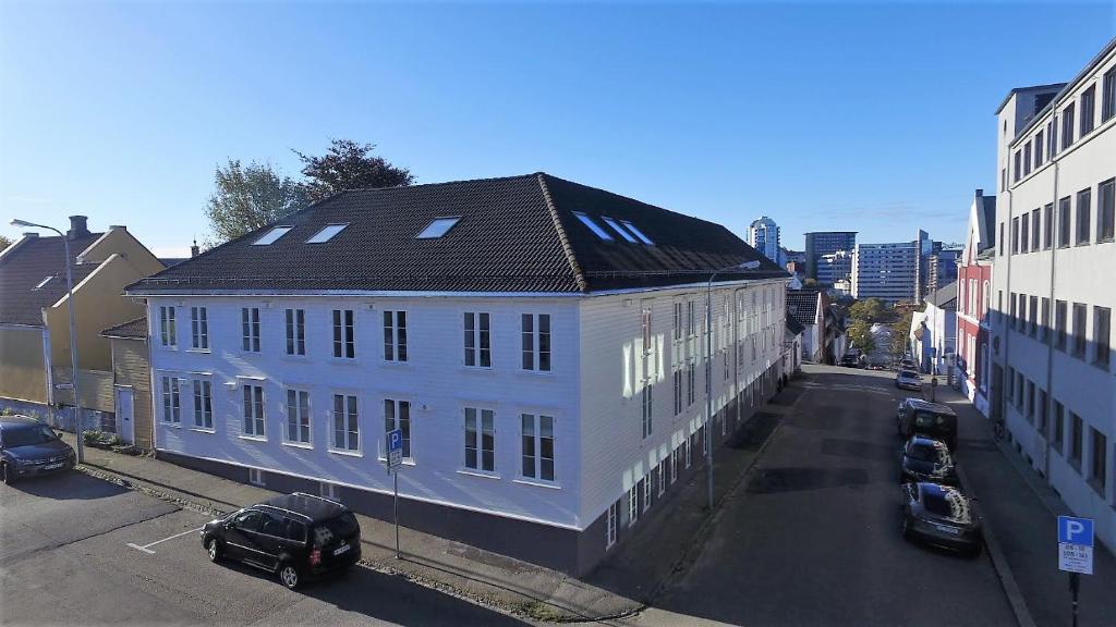 a large white building with a black roof on a street at Stavanger Housing Hotel in Stavanger