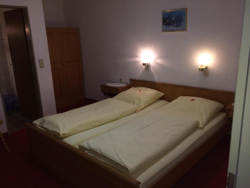 two beds in a bedroom with two lights on the wall at Hotel-Restaurant Hellmann in Schwarzenbruck