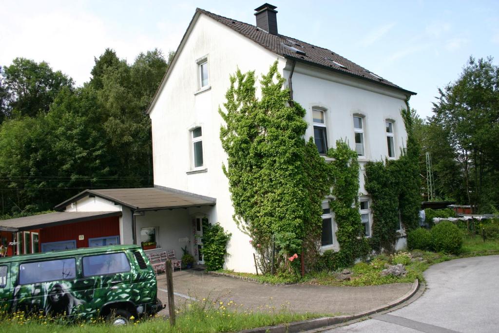 een wit huis met een groene jeep er voor geparkeerd bij Am Buchenberg in Ennepetal