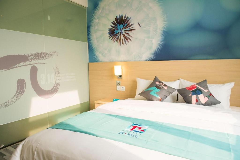 1 dormitorio con 1 cama y una pintura en la pared en Pai Hotel Suining North Xishan Road, en Suining