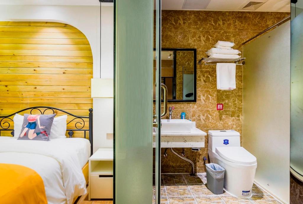 a bathroom with a bed and a sink and a toilet at Pai Hotel Jiuquan Jianshe Road Ouzhou Yuan in Jiuquan